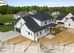 There are houses that have been finished, while others are still being built. There’s a grassy area, roads, and rolled-out architectural blueprints at the bottom, blending into the image