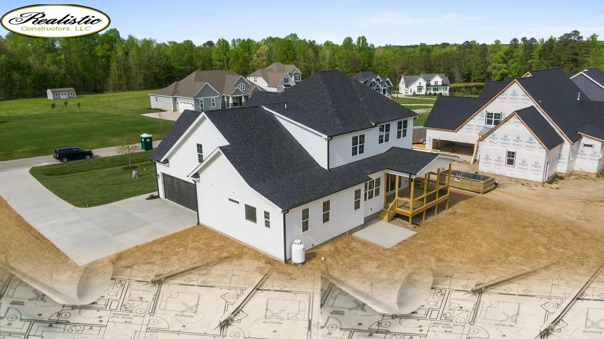 There are houses that have been finished, while others are still being built. There’s a grassy area, roads, and rolled-out architectural blueprints at the bottom, blending into the image
